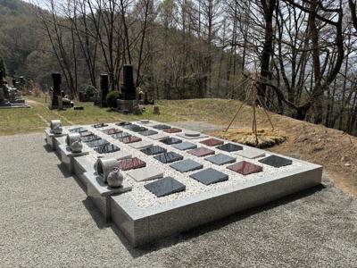 緑に包まれた石碑群と春の光景